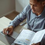 Pessoa organizando uma carteira de investimentos diversificada no notebook e revisando a distribuição de ativos em um caderno.