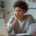 Pessoa analisando gastos no notebook e refletindo sobre consumo consciente enquanto organiza recibos.